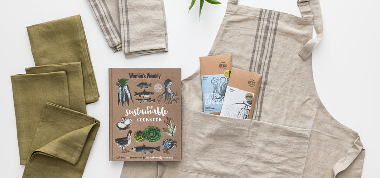 Linen apron, cookbook, linen napkins, tea towels and chocolate featured out of gift box.
