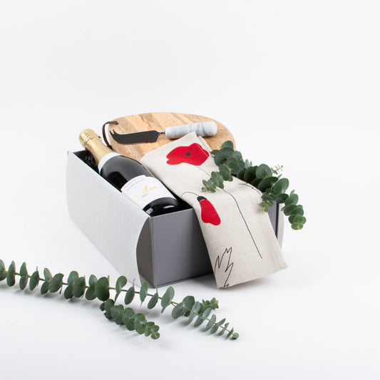 Real estate settlement gift box with bubbles, cotton tea towel, wooden board, and marble cheese knife. A client gift NZ