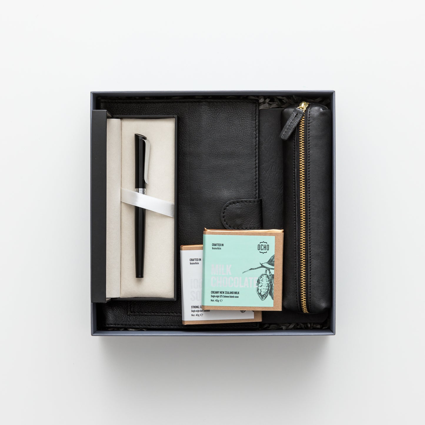 Gift box includes leather notebook cover, notebook and pen, leather pencil pouch, chocolate.