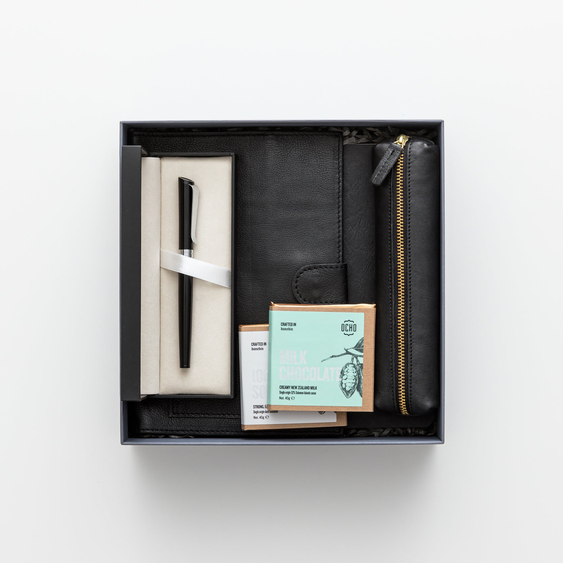 Gift box includes leather notebook cover, notebook and pen, leather pencil pouch, chocolate.