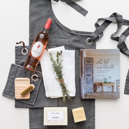 Products displayed out of gift box include apron, pot mitt, tea towel, rose wine, hand towels, book, soap, soap holder, nail brush.