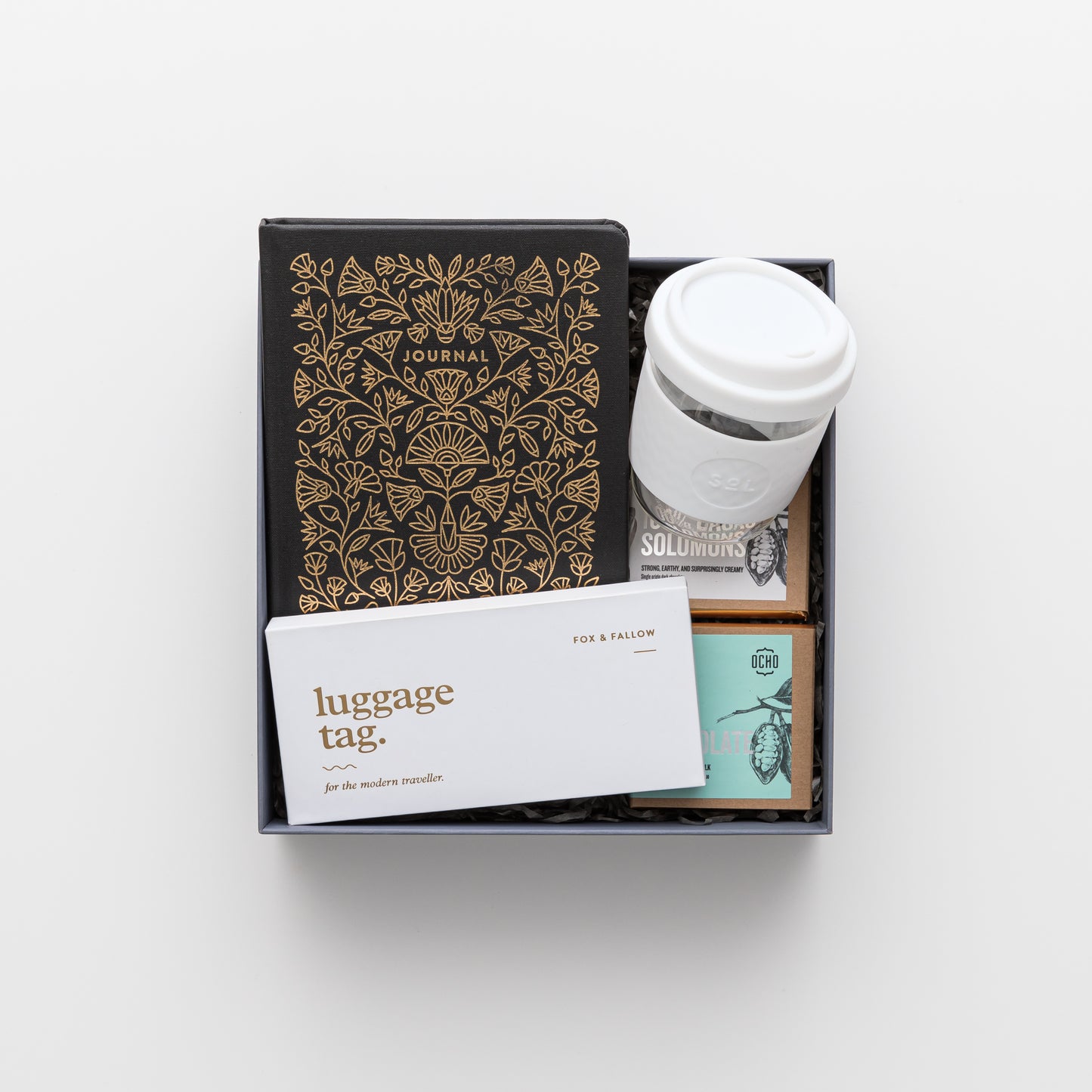 Gift box includes reusable cup, journal, chocolate, luggage tag.