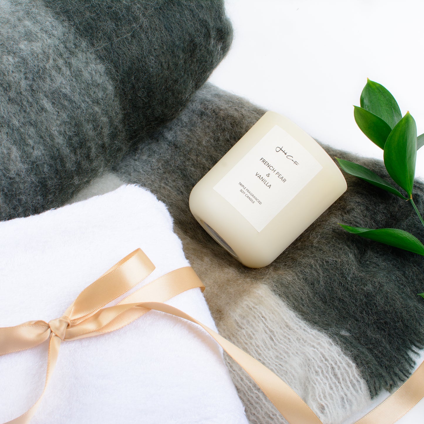 Close up shot of soft throw, candle and towels.