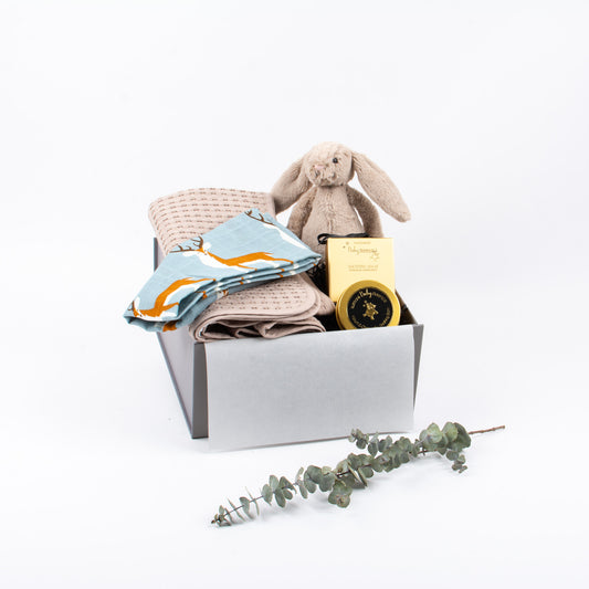 Cotton baby blanket, burp cloth, botanical balm by Surmanti, soft toy by Jellycat.