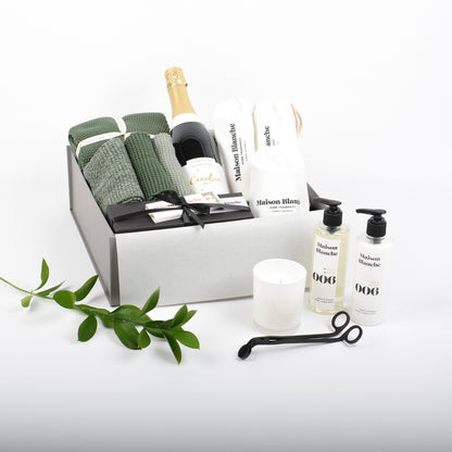 Luxurious bathroom products displayed in gift box. Bubbles, natural cotton hand towles and matching face cloths and gently scented bathroom body products with candle.