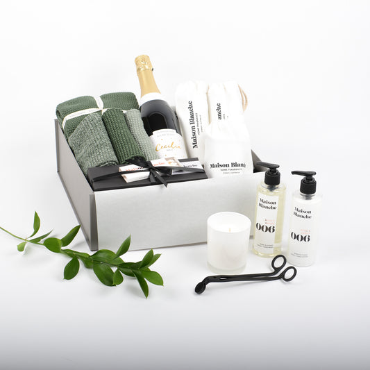 Luxurious bathroom products displayed in gift box. Bubbles, natural cotton hand towles and matching face cloths and gently scented bathroom body products with candle.