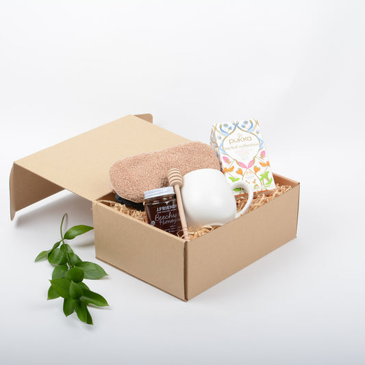 Gift box with a mug, honey and other items nestled in kraft gift box.