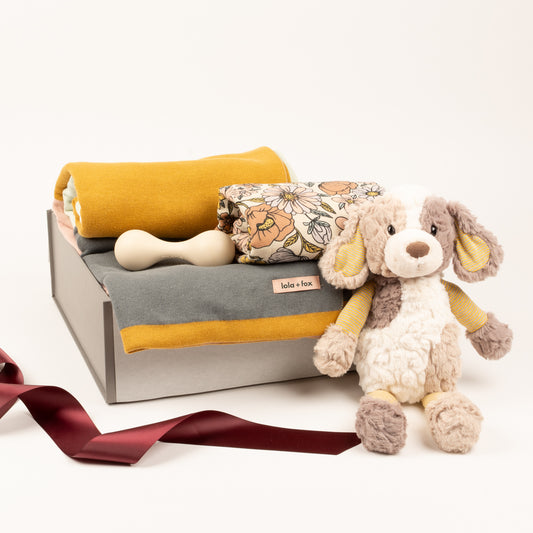 Luxury baby blanket, swaddle by Mushie, rattle and soft toy displayed in gift box.