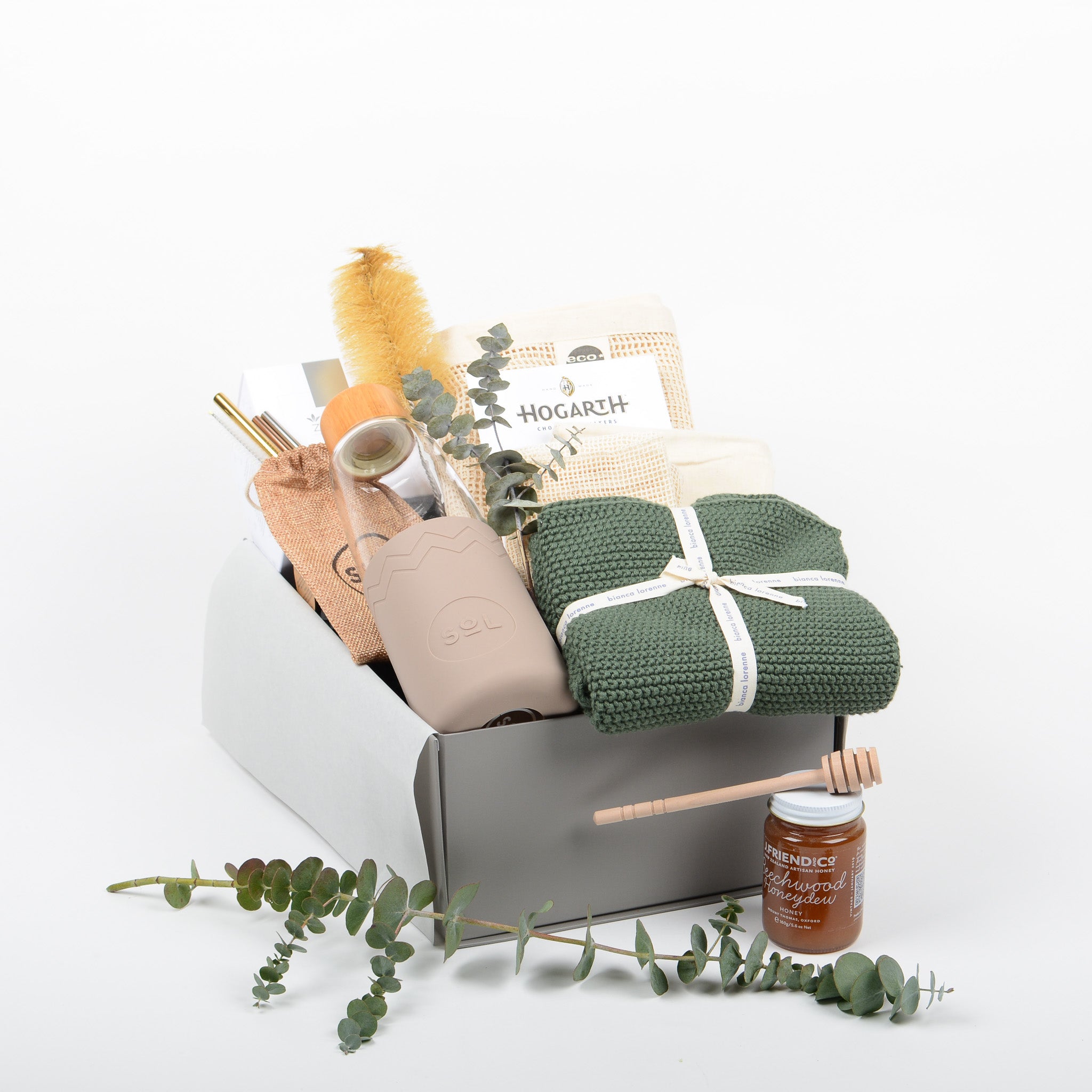 Gift Box with a hand blown glass drinking bottle, cotton hand towel, metal straws, tea, chocolate and honey. 