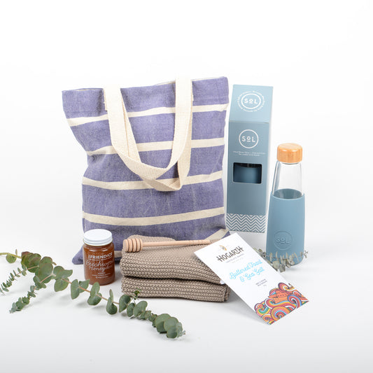 Cotton tote bag with hand blown glass drinking bottle, chocolate, cotton hand towel, artisan honey and dipper.