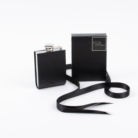A black leather hip flask with a swivel bracket fastener, displayed alongside its black box packaging, on a white background.