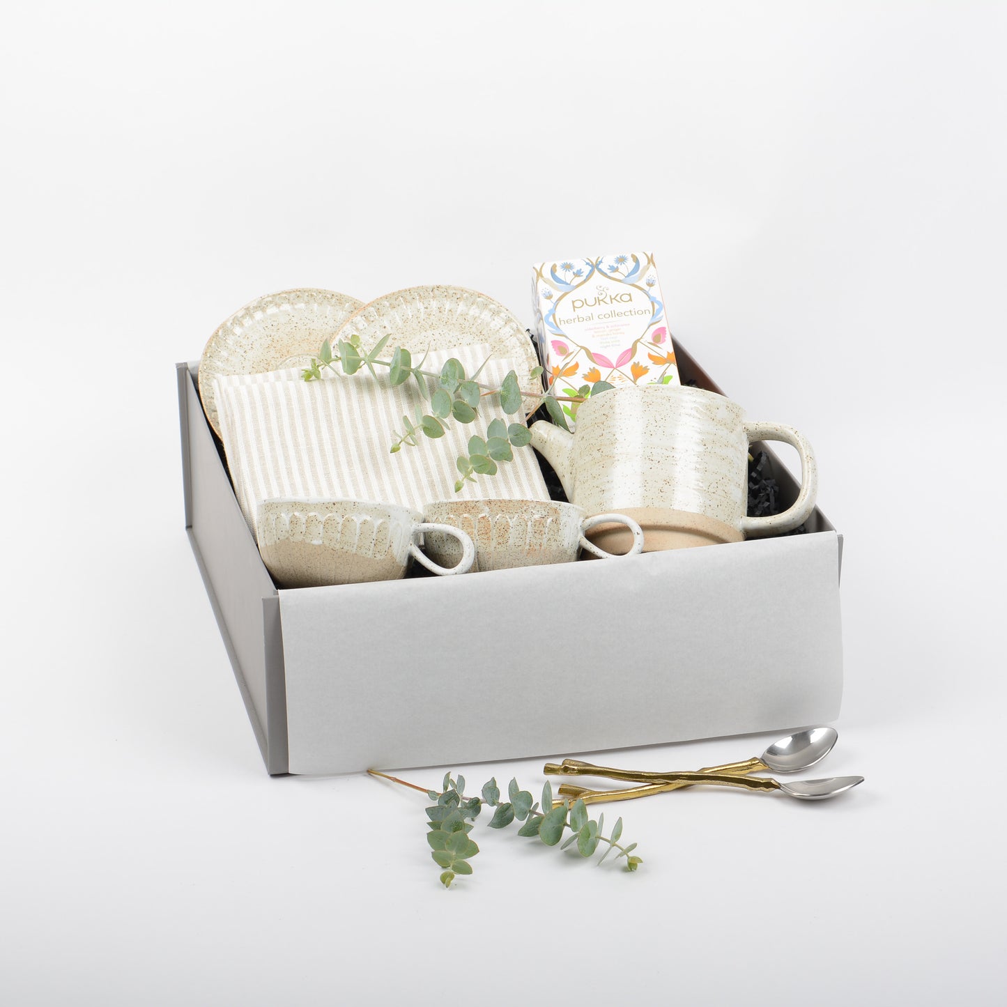 Set of ceramic tea cups, saucers and matching tea pot. Linen napkins and herbal tea are included in a gift box.