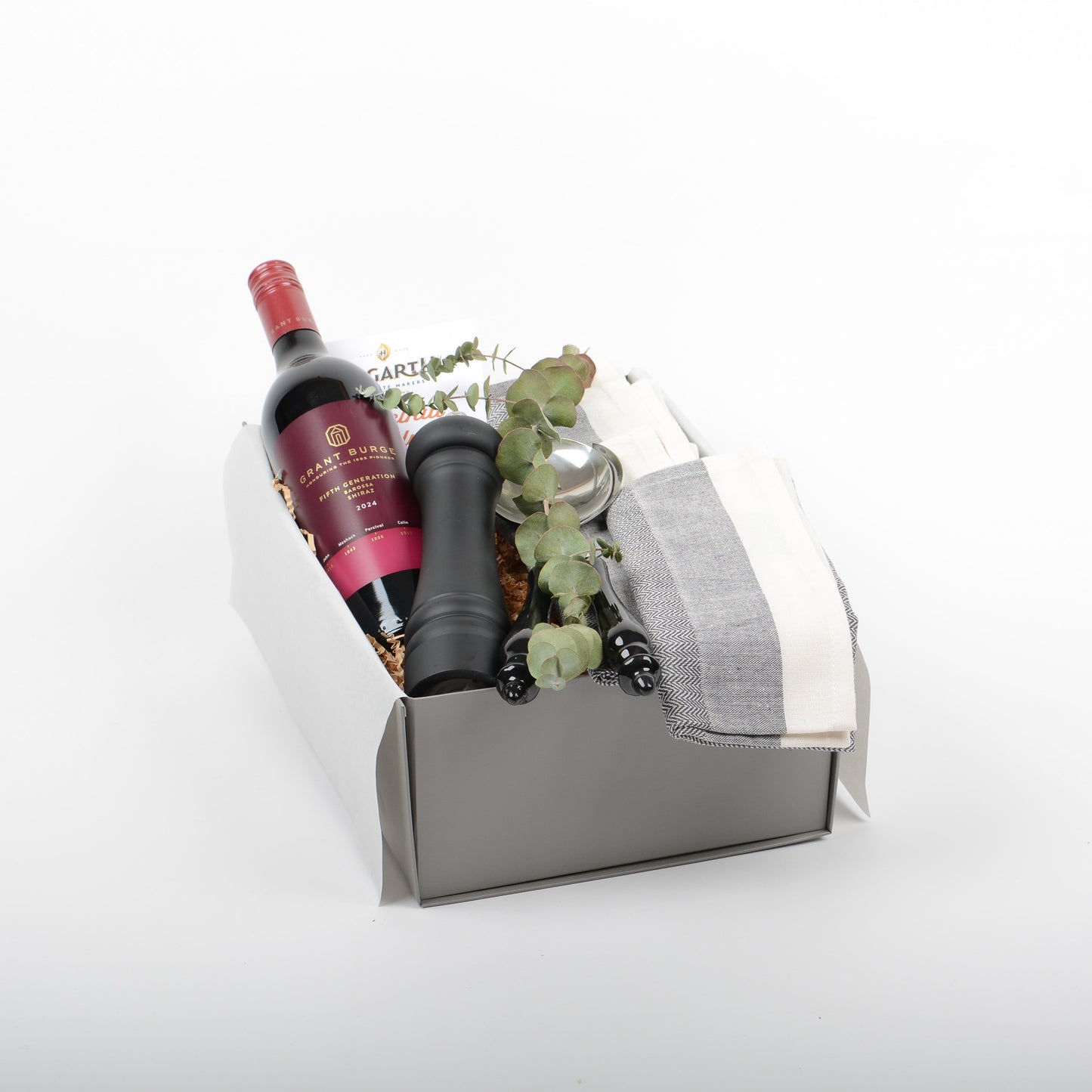 Gift box with wine, salad servers, cotton napkins, pepper mill and chocolate.