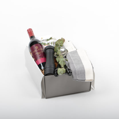 Gift box with wine, salad servers, cotton napkins, pepper mill and chocolate.