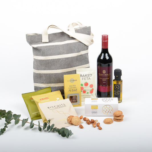 A tote filled with treats, wine, truffle oil.