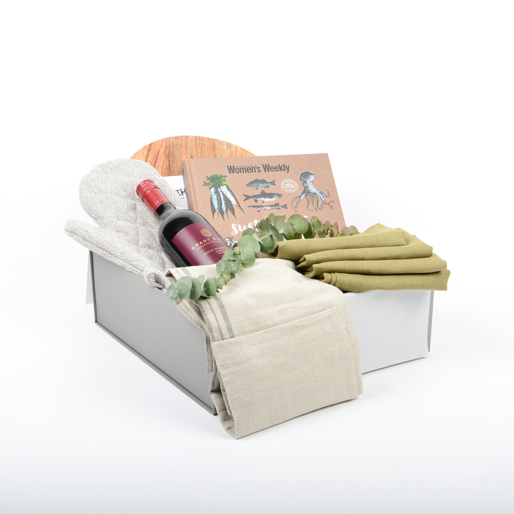 Gift Box includes linen napkins, linen blend apron, fine wine, a sustainbale cookbook, wooden board and oven glove and chocolate.