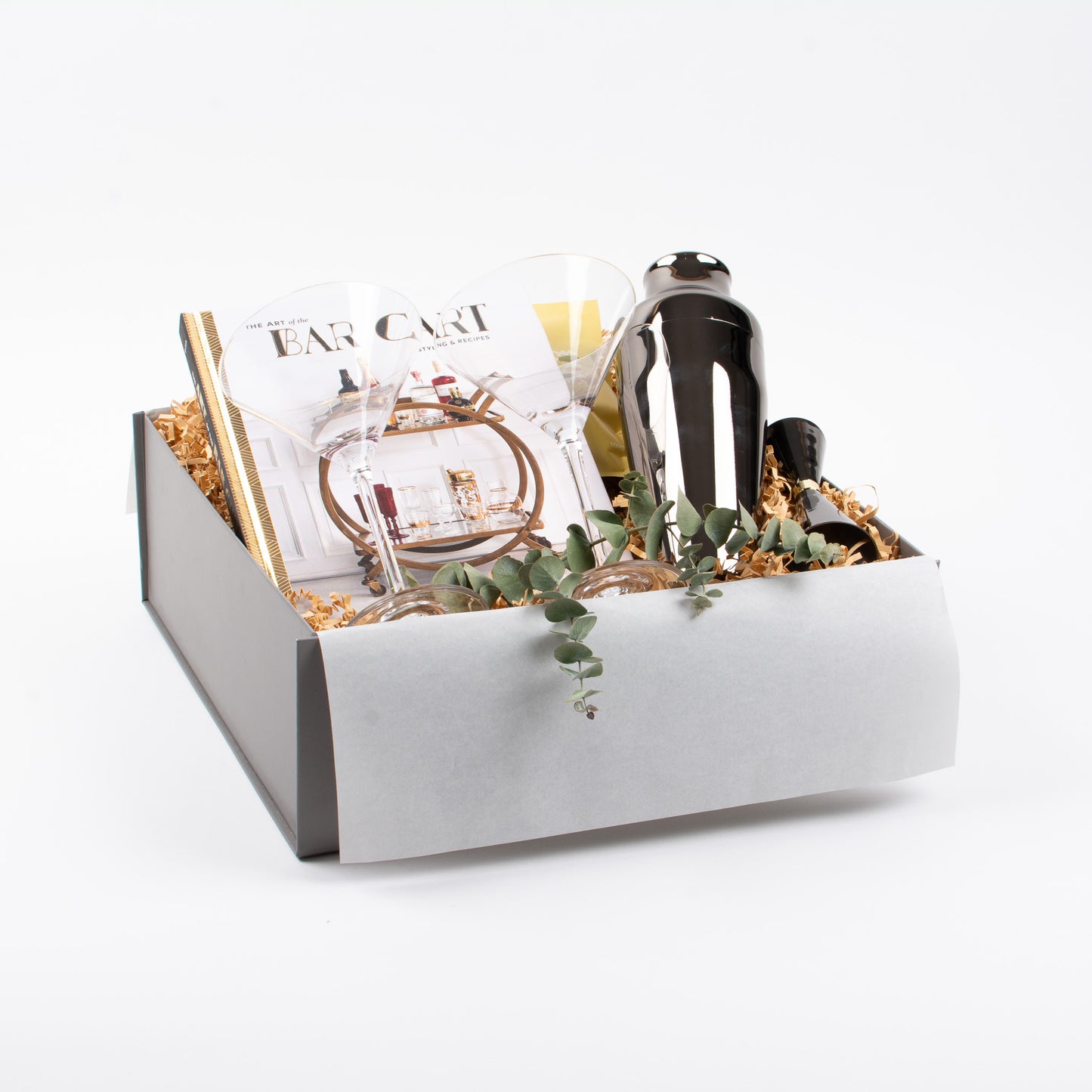 Cocktail gift box with barcart recipe book, shaker, jigger, cocktail glasses, and gourmet treats.