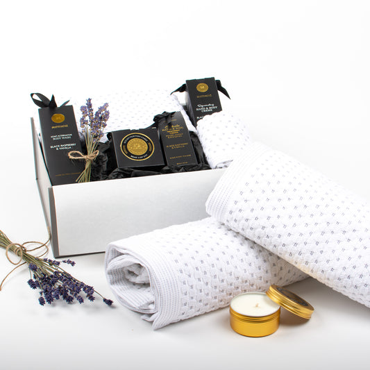 A set of bathroom towels and body products displayed outside of gift box.
