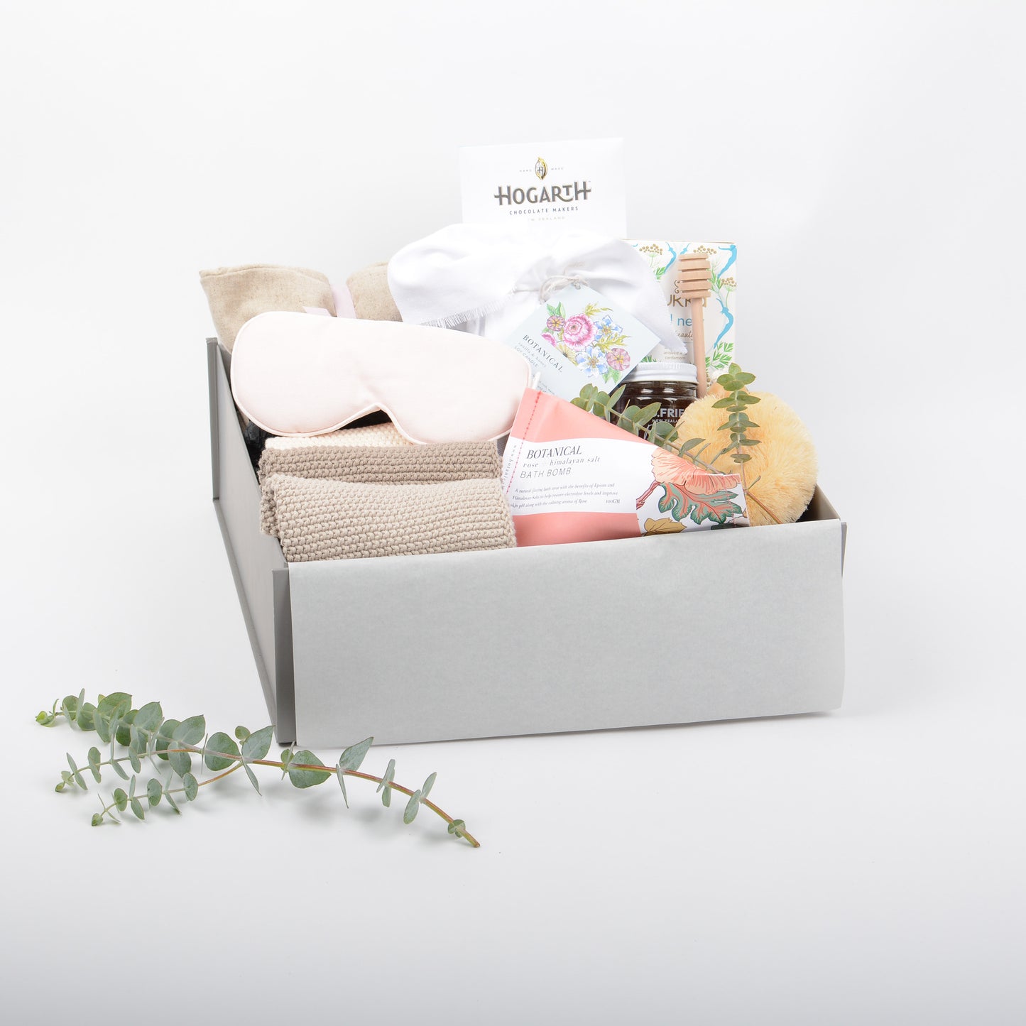 A gift box featuring heat pillow, eye mask, cotton wash cloths, bath bomb, honey tea and scented candle. 