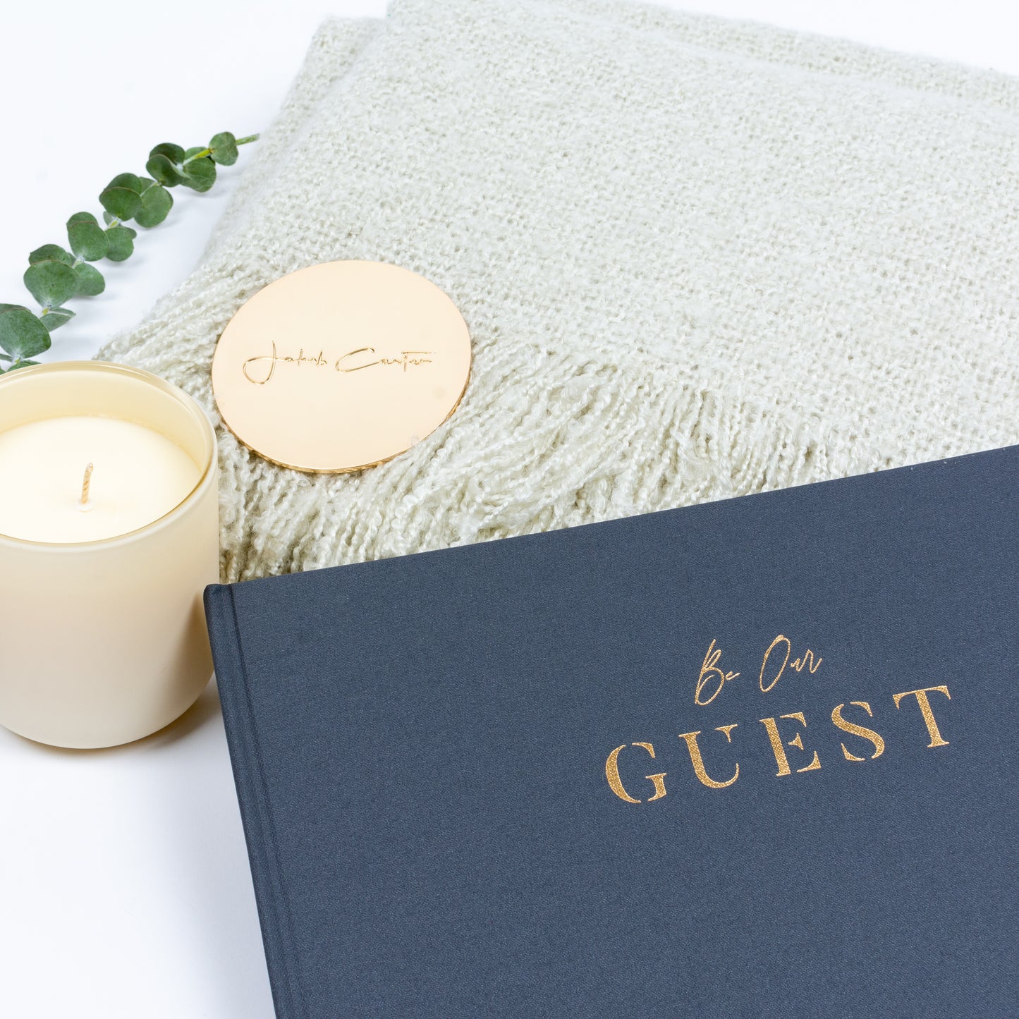 Closeup of guest book, soft throw, scented candle.