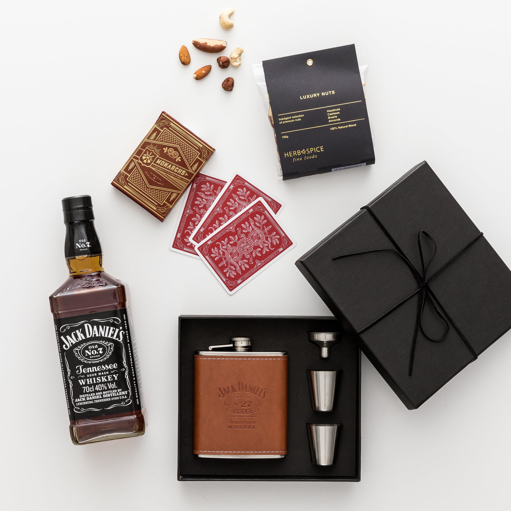 Products displayed out of gift box are whisky, hip flask, cards, nuts.
