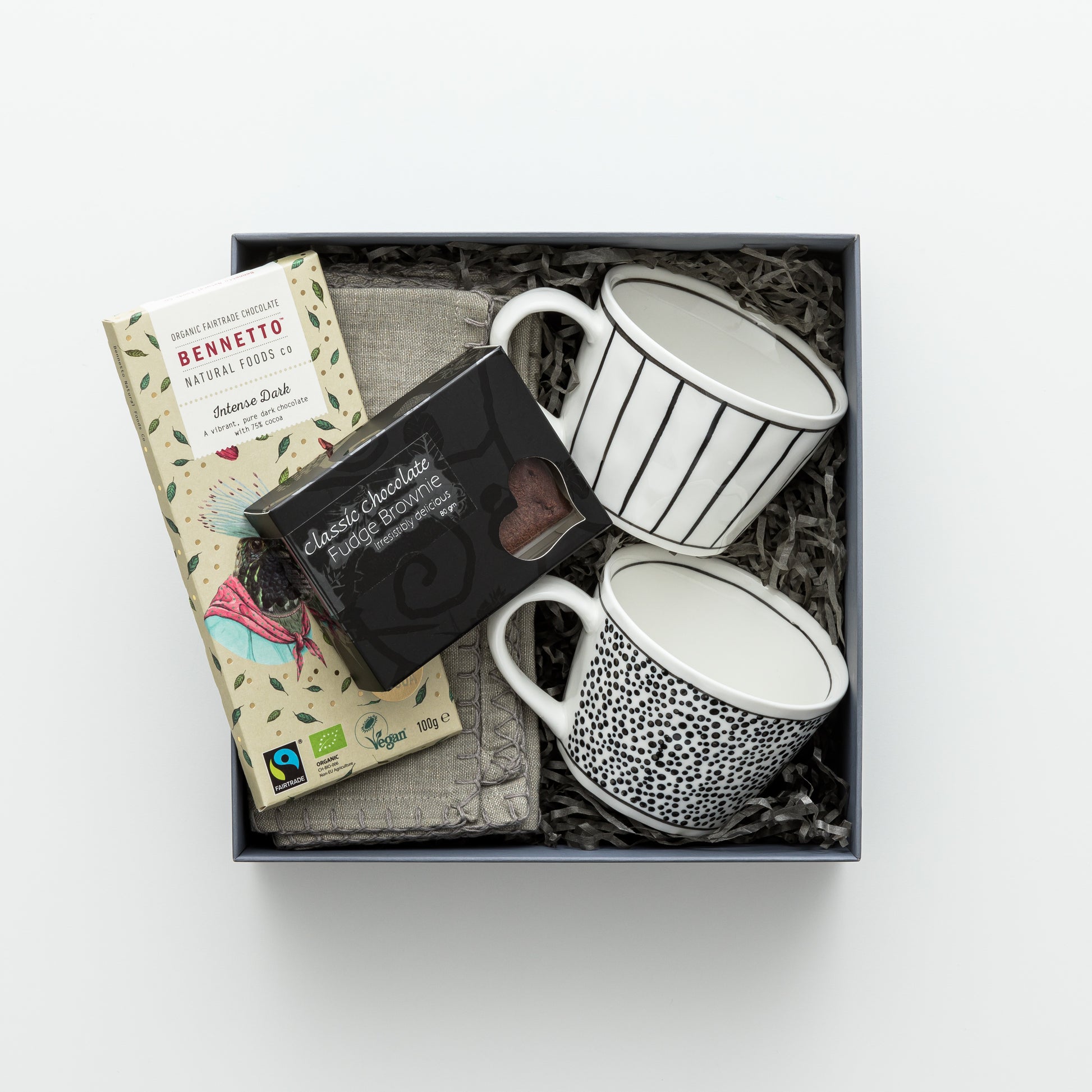 Gift box includes two mugs, two napkins, chocolate, brownie.