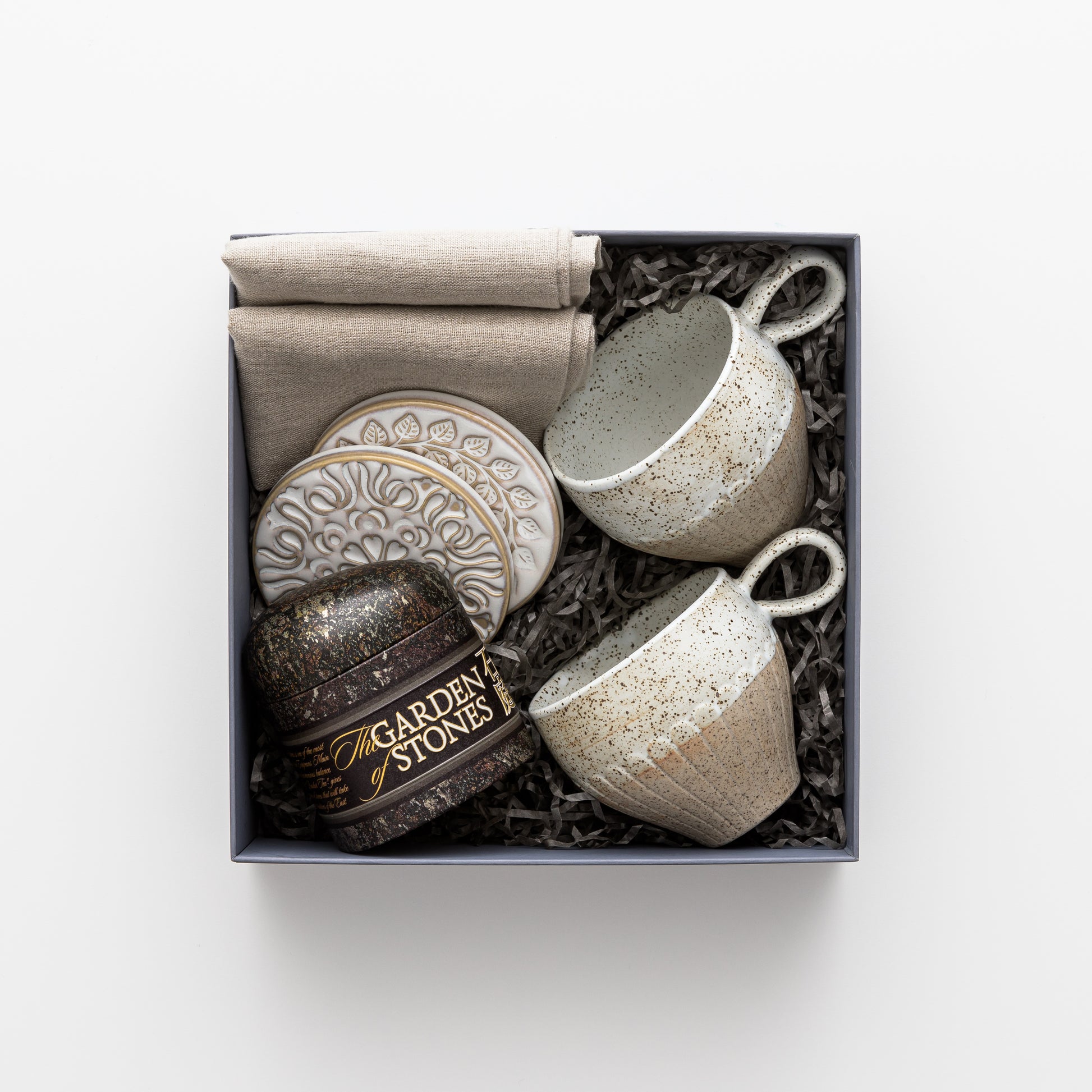 Gift box features two linen napkins, two ceramic mugs, tea, coasters.