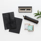 Flatlay of products are leather notebook cover, notebook and pen, leather pencil pouch, chocolate.