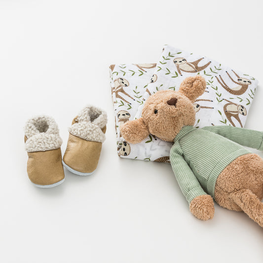 Close up of soft toy, swaddle and shoes shown out of gift box.