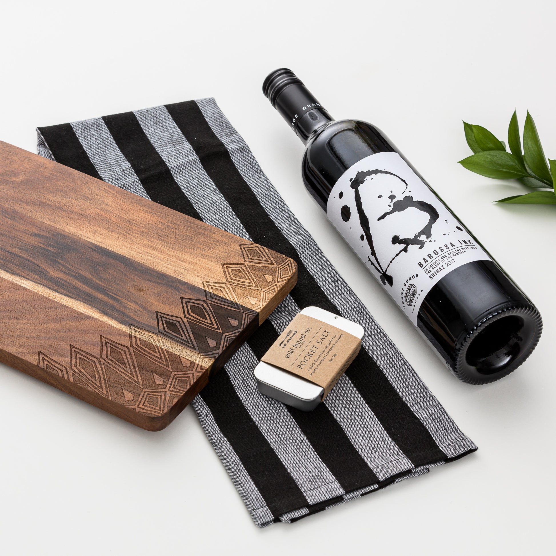 Close up of products displayed out of gift box. Red wine, seasoning, tea towel and decal wooden board.