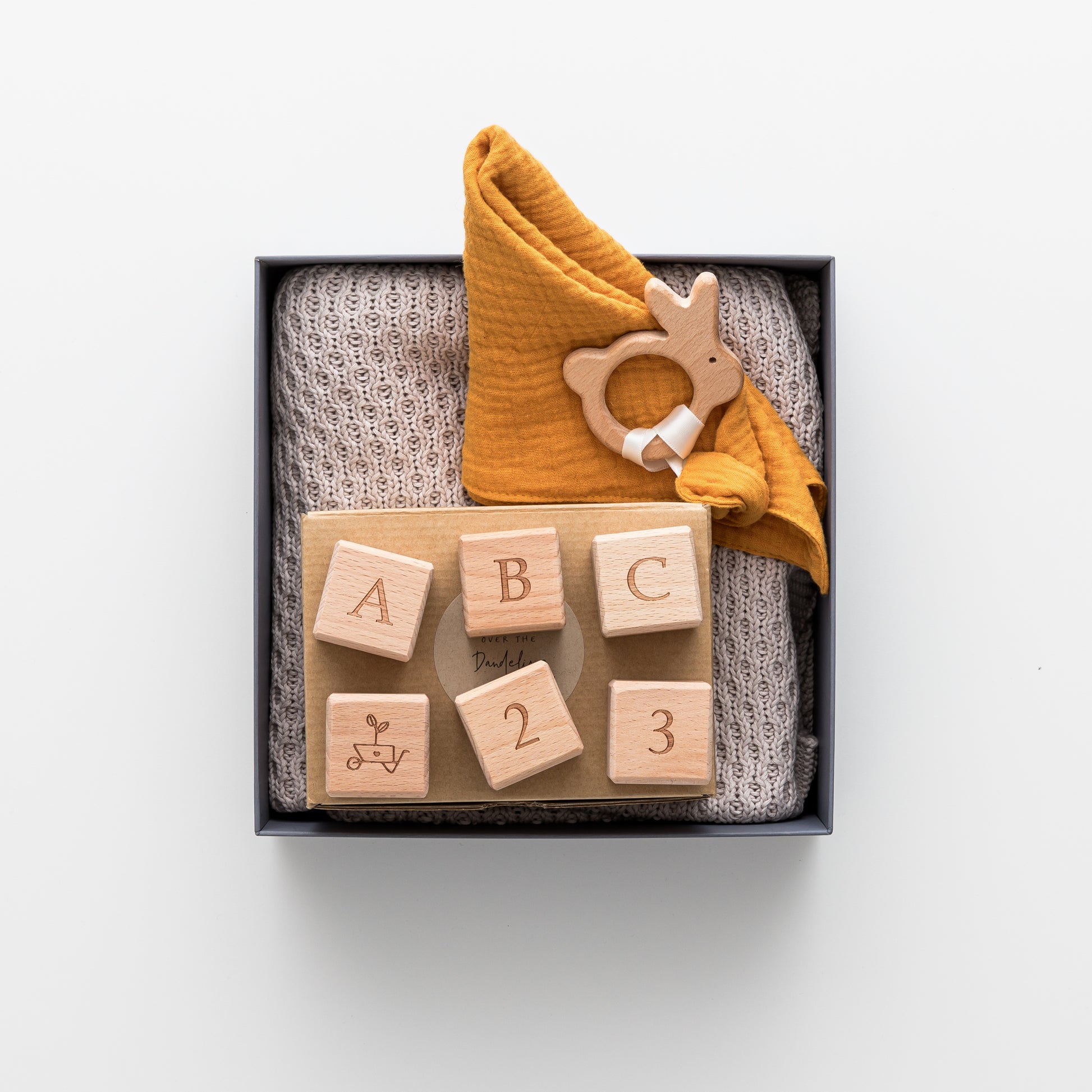 Gift box includes cotton blanket, wooden teether and wooden blocks.