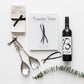 Products featured out of gift box are red wine, cook book, four napkins, salad servers.