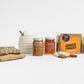 Products featured out of gift box are honey pot and dipper, two jars of honey, biscuits, two tea towels.