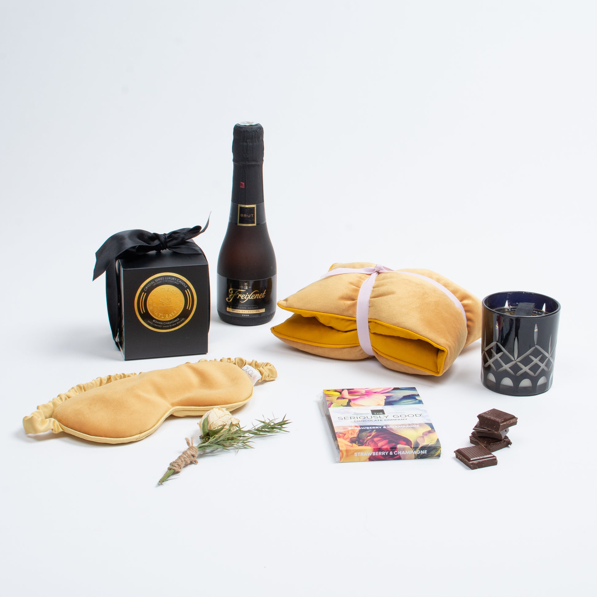 Products shown out of gift box are freixenet, heat wrap, eye mask, chocolate, scented candle.