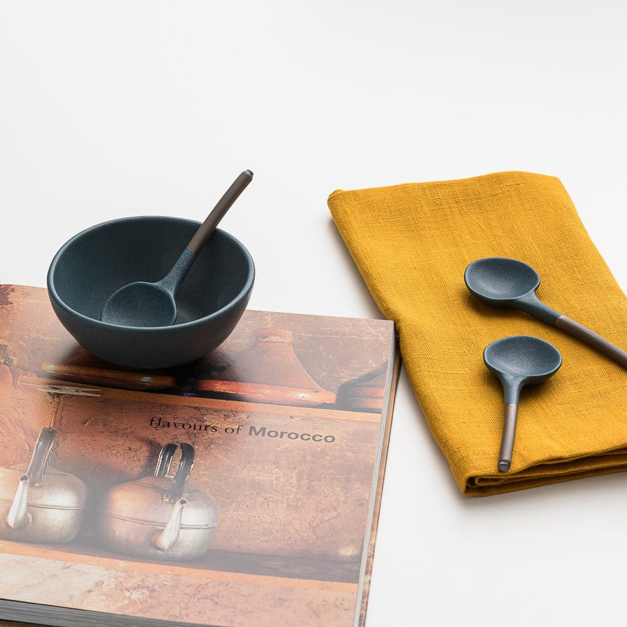 Closeup of linen napkin, ceramic spoons, bowl and cookbook.