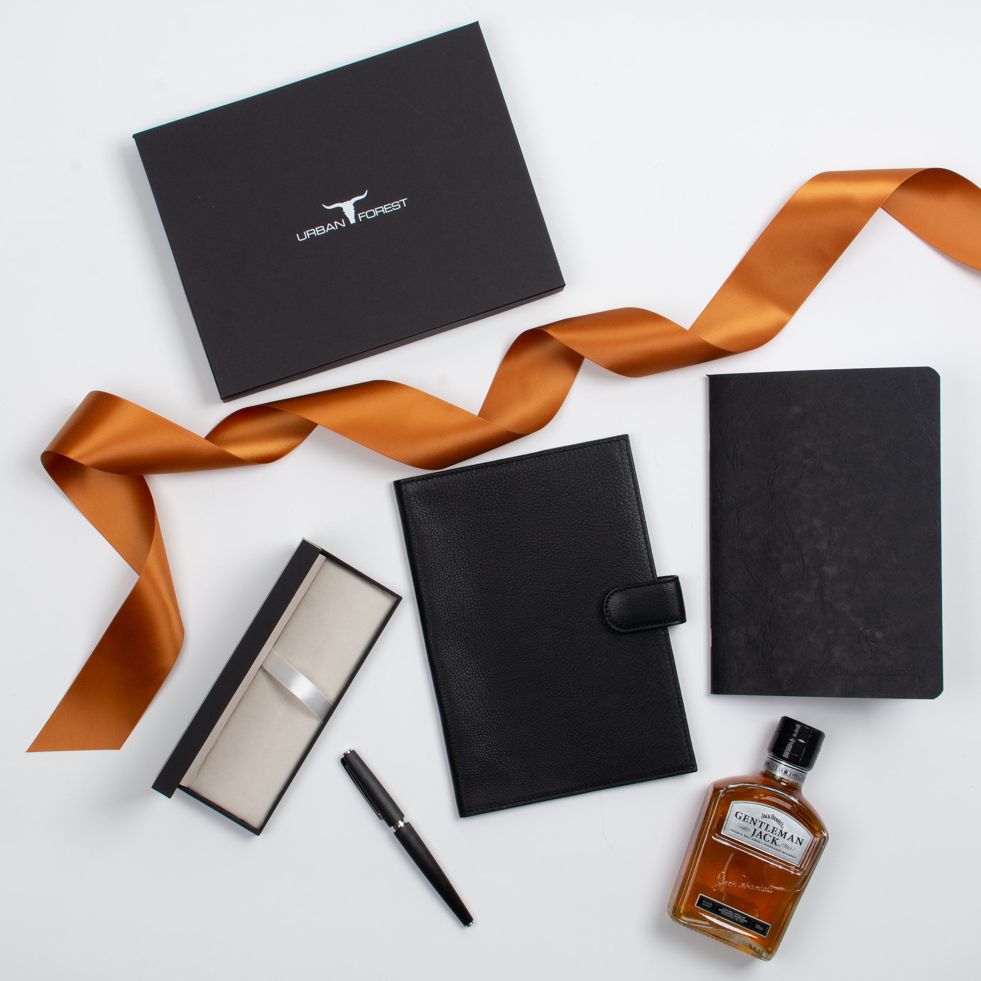 Featured products out of gift box are notebook, notebook cover, pen, whisky.