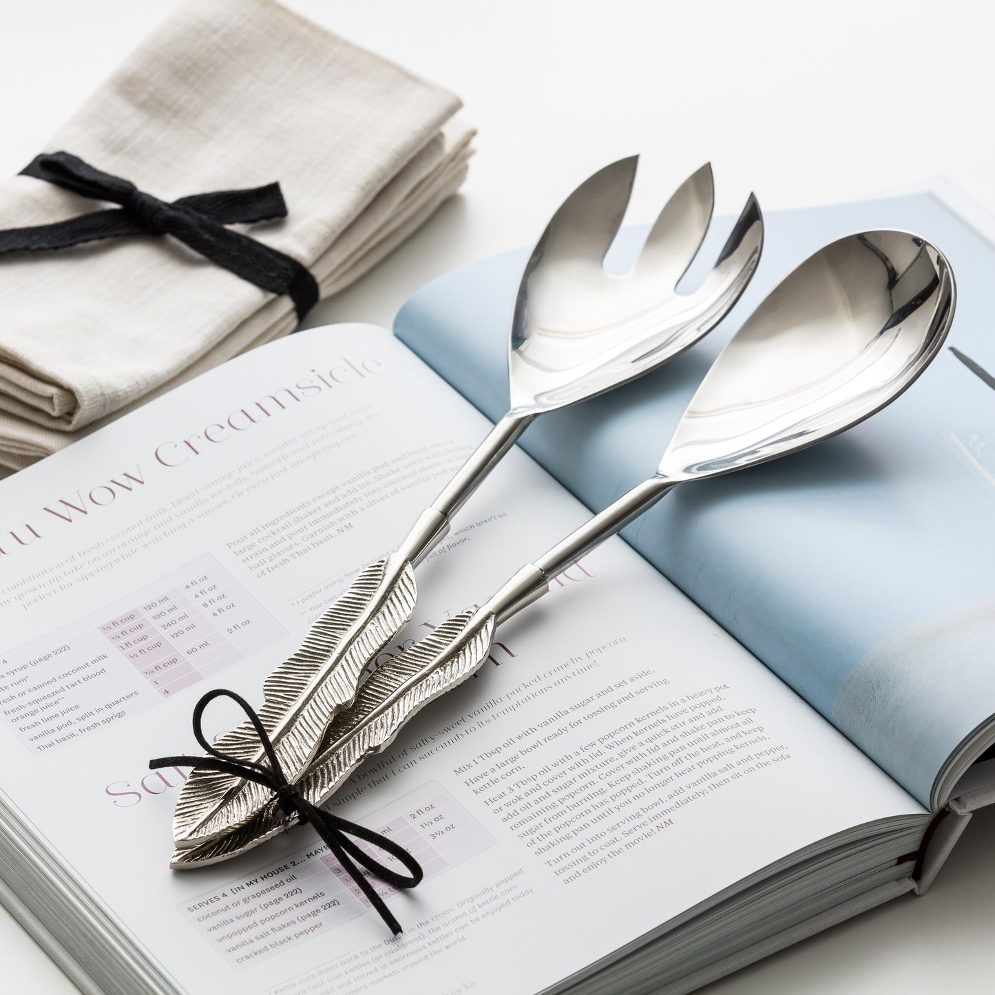 Close up of book, salad servers and cotton napkins